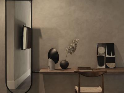 Interior moderno de habitación de hotel con espejo redondo, televisor, esculturas y estante de madera en pared gris.