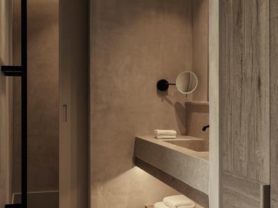 Baño moderno con detalles en madera clara, gran espejo y toallas debajo del lavabo.