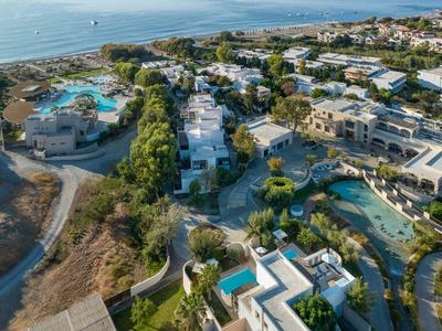 Vista aérea de un resort con varias piscinas, edificios y vista al mar al fondo.
