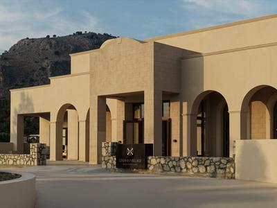 Fachada de hotel con arcos y muros beige bajo un cielo azul con montaña al fondo.