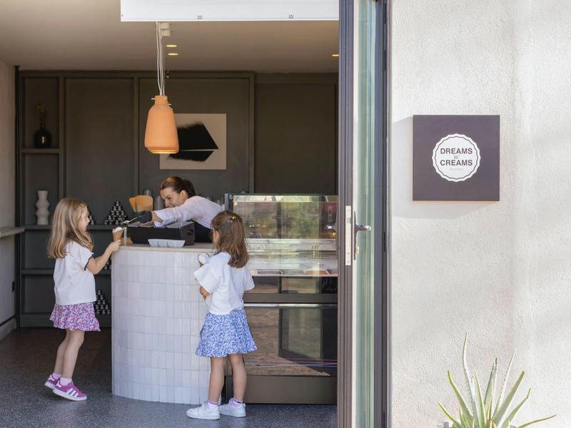 Tres niños están junto a un mostrador moderno de recepción en una zona luminosa del hotel.
