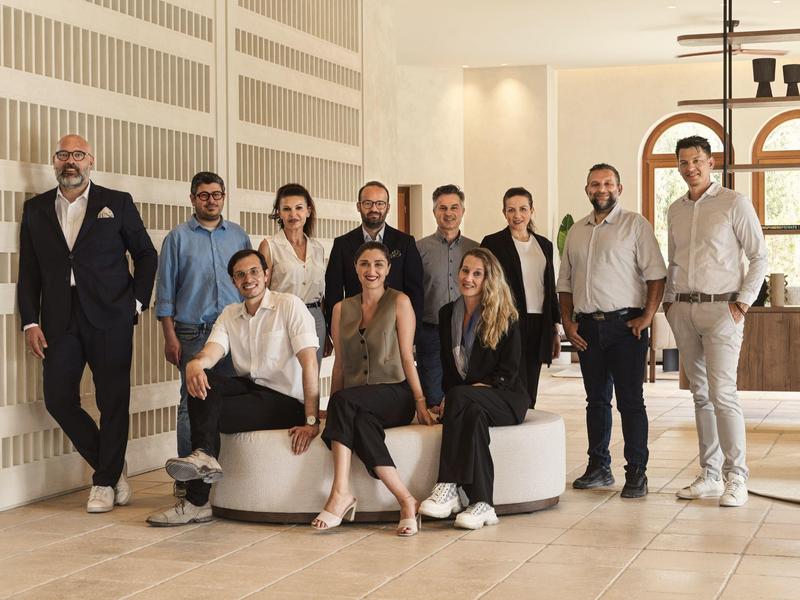 Grupo de diez personas con ropa profesional en un interior moderno y luminoso de un hotel.
