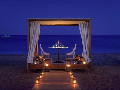 Cena romantica sotto un lounge coperto sulla spiaggia di notte con vista mare.