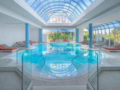 Innenbereich mit attraktivem Schwimmbecken und Relax-Liegen bei Tageslicht.