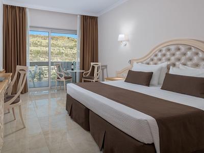 Helles Doppelzimmer mit Balkon, braunen Vorhängen und modernen Möbeln.