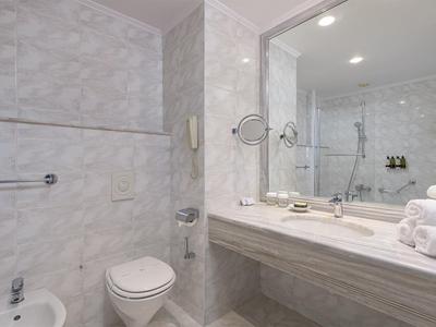 Modernes Badezimmer mit Marmorwänden, Waschbecken und Toilette in einem Hotelzimmer.