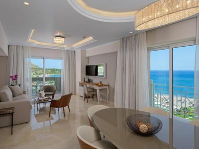 Helles Wohnzimmer mit Meerblick, moderner Einrichtung und Esstisch in einem Hotelzimmer.