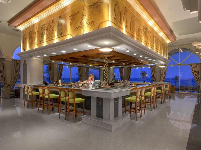 Elegante Hotelbar mit Holzakzenten, Barhockern und Panoramafenstern bei Nacht.