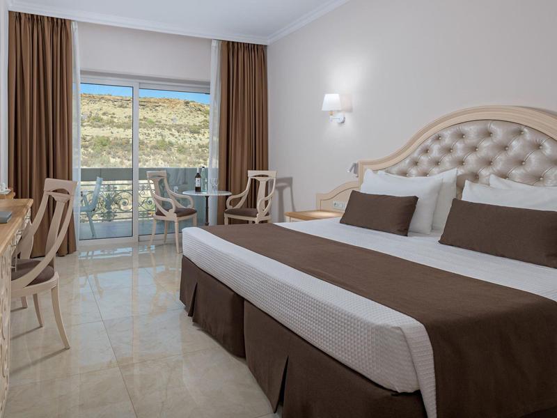 Helles Doppelzimmer mit Balkon, braunen Vorhängen und modernen Möbeln.