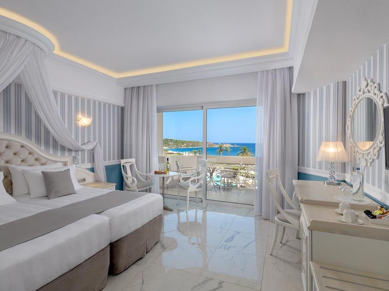 Helles Hotelzimmer mit Doppelbett, Meerblick und elegantem Interieur.