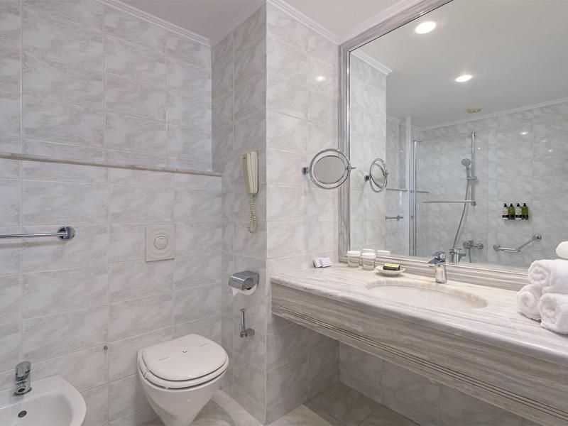 Modernes Badezimmer mit Marmorwänden, Waschbecken und Toilette in einem Hotelzimmer.