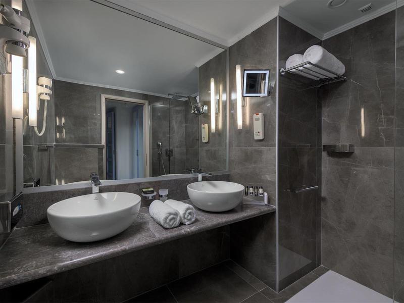 Modernes Badezimmer mit doppeltem Waschbecken und glasierter Duschkabine.