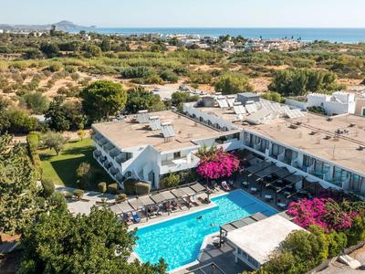 Hotel mit großem Pool, umgeben von Bäumen, in ländlicher Gegend nahe Meer gelegen.