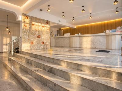 Moderner Hotellobby mit Marmorboden, Rezeptionstresen und warmem Licht.
