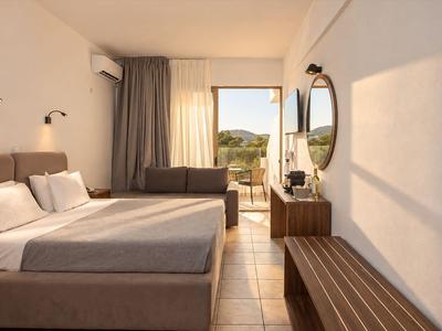 Helles Hotelzimmer mit Doppelbett, Sitzgelegenheit, Schrank und Balkon mit Ausblick.