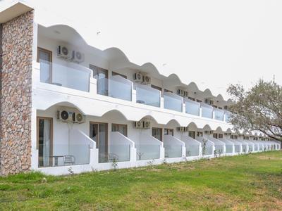 Moderner Hotelkomplex mit weißen Balkonen und grüner Wiese im Vordergrund.