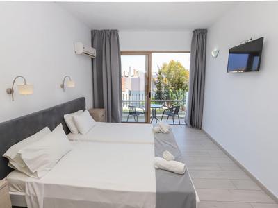 Lichte hotelkamer met twee eenpersoonsbedden, balkon en tv aan de muur