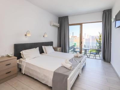 Hell eingerichtetes Hotelzimmer mit zwei Einzelbetten und Balkon mit Stadtblick.