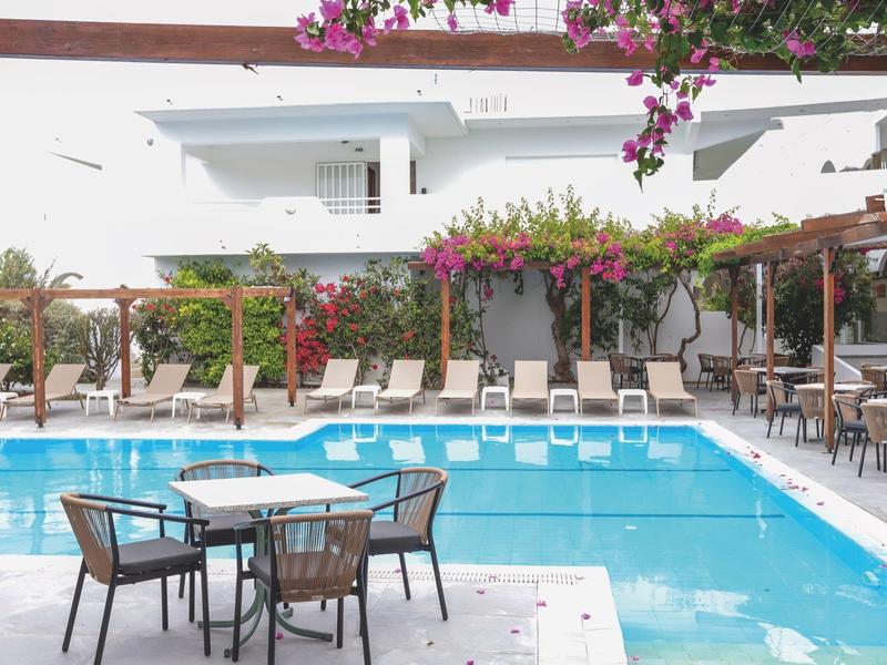 Moderne zwembadgedeelte met witte ligstoelen en bloeiende bougainvillea in een hotelomgeving.