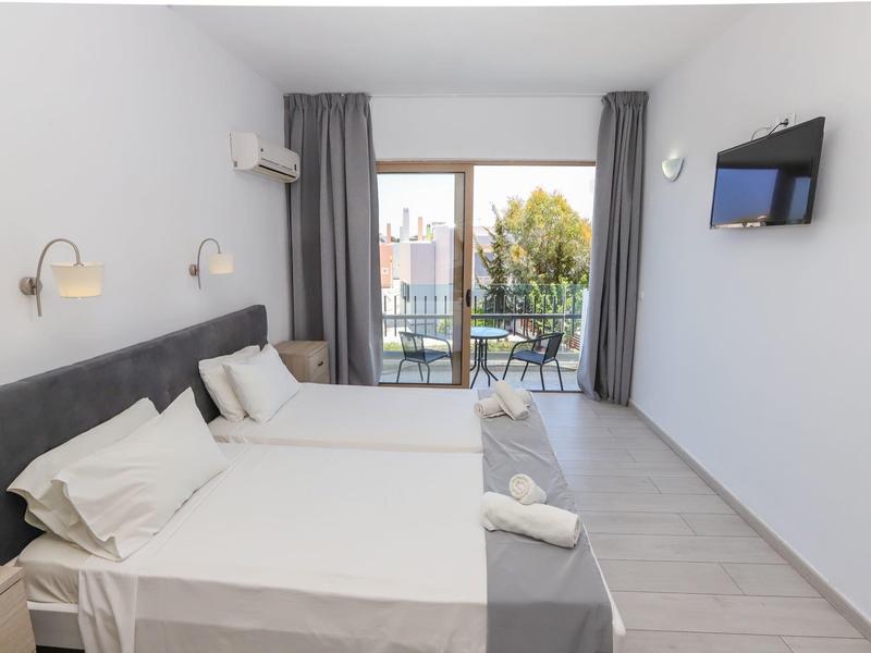 Lichte hotelkamer met twee eenpersoonsbedden, balkon en tv aan de muur