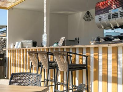Moderner Barbereich mit hohen Holzhockern und Lichtdurchflutung im Hotel