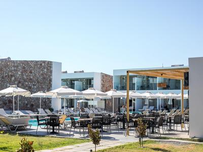 Moderner Hotelpoolbereich mit Liegestühlen, Sonnenschirmen und Außenessbereich bei klarem Himmel.