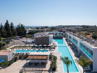 Moderner Hotelkomplex mit zwei langen Pools, Liegestühlen und Blick auf das Meer.
