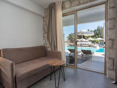 Gemütlicher Innenbereich mit Sofa und Blick auf den Pool im Außenbereich eines Hotels.