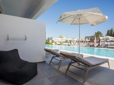 Moderner Poolbereich mit Liegestühlen, Sonnenschirm und Sitzsack neben Hotelterrasse.