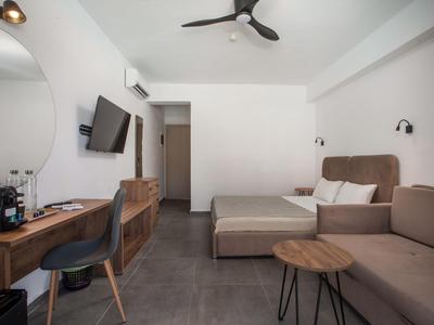 Modernes Hotelzimmer mit Doppelbett, Sofa, Schreibtisch und Wandfernseher.