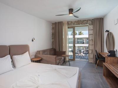 Modernes Hotelzimmer mit Doppelbett, Sofa, Schreibtisch und Balkon mit Meerblick.