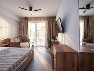 Helles Hotelzimmer mit Doppelbett, Sofa, Balkon und modernen Holzmöbeln.