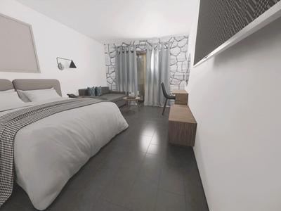 Modernes Hotelzimmer mit großem Bett, Sessel und Fenstervorhängen in neutralen Farben.