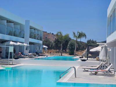 Moderner Hotelpool mit Liegestühlen und Palmen unter klarem blauem Himmel.
