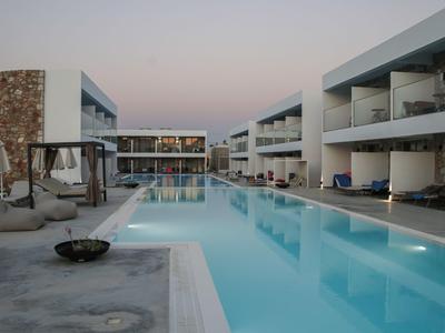 Moderner Hotelpool mit Liegestühlen und Balkonen bei Dämmerung.