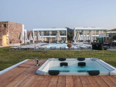 Moderne Hotelanlage mit beheiztem Whirlpool und Schwimmbecken im Garten bei klarem Himmel.