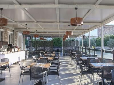 Große Hotelterrasse mit Tischen und Stühlen sowie Buffetbereich unter einem weißen Dach.
