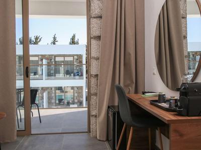 Blick aus einem Hotelzimmer mit Schreibtisch und Stuhl auf einen Balkon mit Meerblick.