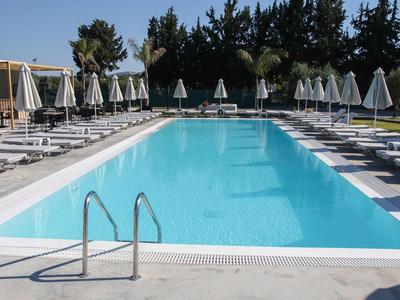 Klares blaues Schwimmbecken mit Liegestühlen und Sonnenschirmen an einem sonnigen Tag.