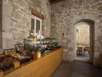 Rustikaler Frühstücksraum mit Steinwänden und Holztheke voller Gebäck und Marmeladen.