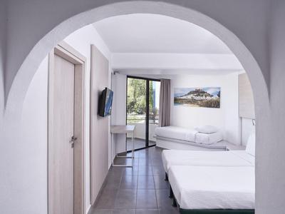 Hell eingerichtetes Hotelzimmer mit zwei Betten, Bogen, Fernseher und Balkonblick.