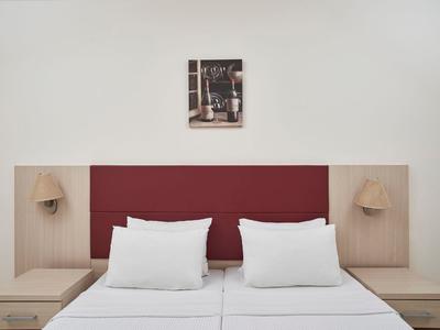 Modernes Hotelzimmer mit zwei Betten, roten Polsterkopfteil und minimalistischer Wanddekoration.