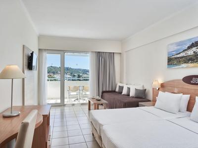 Helles Hotelzimmer mit Doppelbett, Sofa, Schreibtisch und Balkon mit Blick auf das Meer.