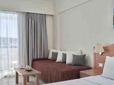 Helles Hotelzimmer mit Sofa, Kissen, kleinem Tisch und Blick auf die Berge durch Fenster.