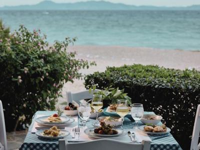 Ein gedeckter Tisch mit Speisen und Getränken am Strand mit Blick aufs Meer.