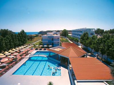 Resort with large swimming pool, sun loungers, umbrellas, and buildings surrounded by trees.