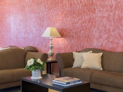 Wohnzimmer mit zwei braunen Sofas, einem schwarzen Couchtisch, einer Lampe und rosa Wand.