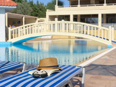 Poolbereich mit einer Brücke und Liegestühlen mit Sonnenhut und Brille.