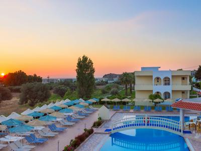Hotelpool mit blauen Liegestühlen und Sonnenschirmen bei Sonnenuntergang