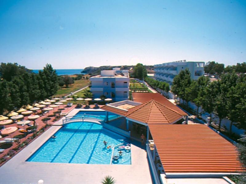 Resort with large swimming pool, sun loungers, umbrellas, and buildings surrounded by trees.